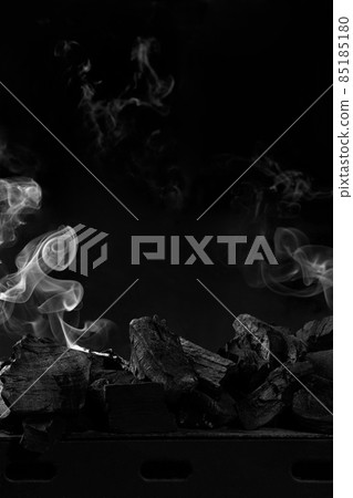 Extinguished coals on grill barbecue on black background with white smoke 85185180