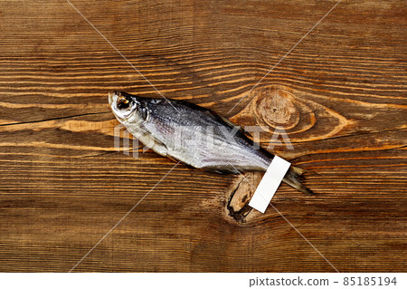 Air-dried silver bream with label on tail lying on wooden surface 85185194