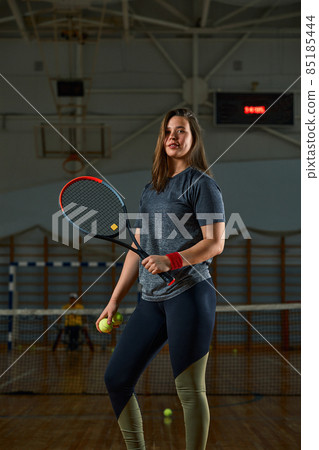 Female tennis player with racket and ball on gym background 85185444
