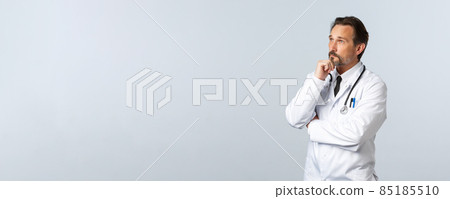 Covid-19, coronavirus outbreak, healthcare workers and pandemic concept. Thoughtful therapist, male doctor in white coat making decision, solving disease case in hospital, thinking as looking left 85185510