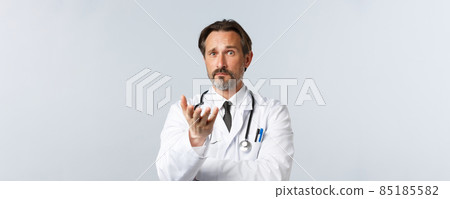 Covid-19, preventing virus, healthcare workers and vaccination concept. Confused and shocked doctor look at strange thing, pointing camera and stare perplexed, cant understand, white background Covid-19, preventing virus, healthcare workers and vaccination concept. Confused and shocked doctor look at strange thing, pointing camera and stare perplexed, cant understand, white background 85185582