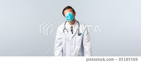 Covid-19, preventing virus, healthcare workers and vaccination concept. Reluctant and tired doctor pull mask on whole face and stooping exhausted, standing white background 85185589