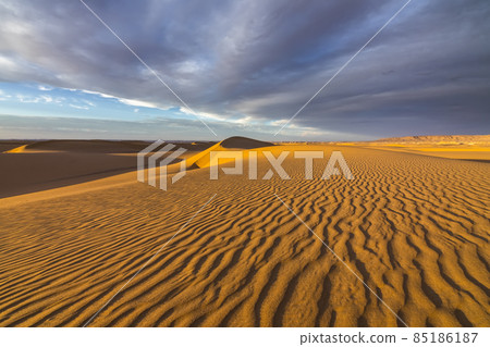 Sunset over the sand dunes in the desert. Arid landscape of the Sahara desert. 85186187
