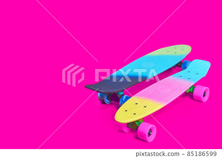 Two rainbow plastic Penny board skateboards on crimson background Two rainbow plastic Penny board skateboards on crimson background 85186599
