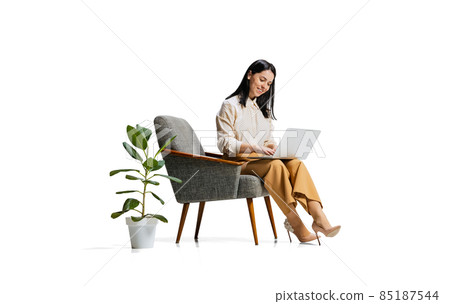 Full-length portrait of young smiling woman, office worker typing on laptop, making business schedule isolated over white background Full-length portrait of young smiling woman, office worker typing on laptop, making business schedule isolated over white background 85187544
