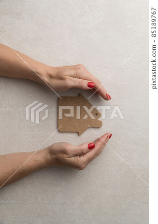 concept of protection and love for the home. flat model of a wooden house with female hands concept of protection and love for the home. flat model of a wooden house with female hands 85189767