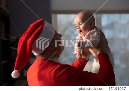 Caucasian grandfather in red hat playing with granddaughter at home selebrating Christmas 85191037
