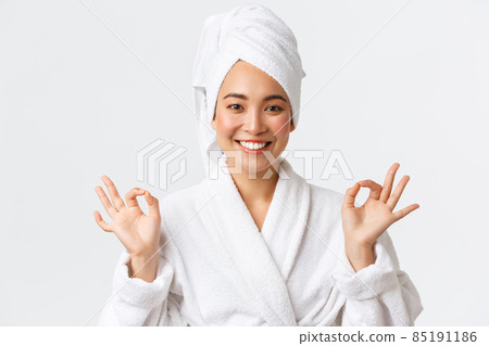 Personal care, women beauty, bath and shower concept. Close-up of relieved attractive asian woman attend spa beauty salon, wear bath towel and bathrobe, meditating, feeling nirvana, smiling Personal care, women beauty, bath and shower concept. Close-up of relieved attractive asian woman attend spa beauty salon, wear bath towel and bathrobe, meditating, feeling nirvana, smiling 85191186