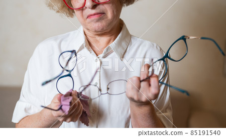 An elderly Caucasian woman chooses glasses from her home collection 85191540