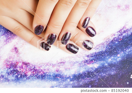 manicure stylish concept: woman fingers with nails purple glitter on nails like cosmos, universe background manicure stylish concept: woman fingers with nails purple glitter on nails like cosmos, universe background 85192040