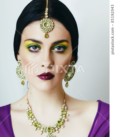 young pretty caucasian woman like indian in ethnic jewelry closeup on white, bridal bright makeup fashion people 85192043