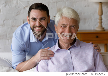 Head shot portrait young man cuddling old father. 85192247