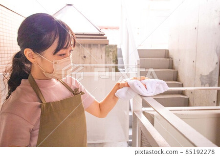 A young woman wiping the common area of an apartment with a rag 85192278