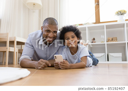 Happy African American daddy and son relaxing on heating floor 85192407