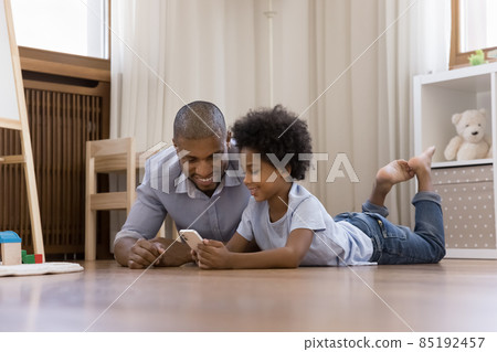 Happy Black kid boy and dad resting on warm floor 85192457
