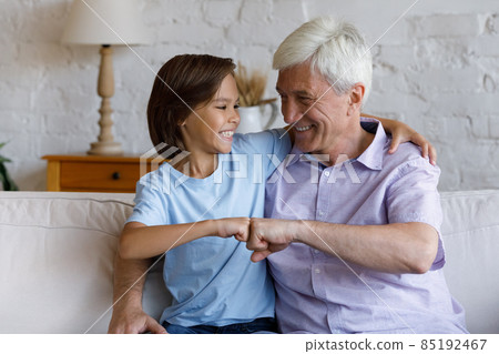 Happy preteen kid boy bumping fists with old grandfather. Happy preteen kid boy bumping fists with old grandfather. 85192467