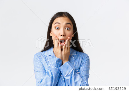 Close-up shot of amazed and impressed, excited pretty asian girl looking in awe with dropped jaw and hands on face, stare at camera astounded with great big news, white background 85192529