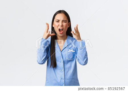 Mad outraged asian girl in blue pajamas arguing, having argument with girlfriend during sleepover, swearing or cursing someone, shaking hands angry, standing white background Mad outraged asian girl in blue pajamas arguing, having argument with girlfriend during sleepover, swearing or cursing someone, shaking hands angry, standing white background 85192567