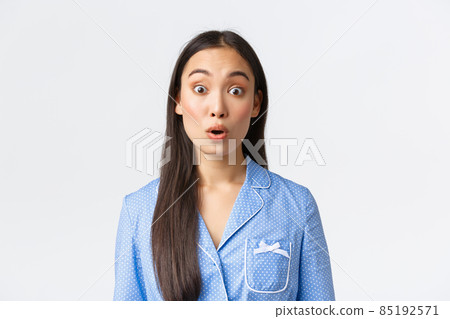 Close-up of startled and shocked asian girl in blue pajama seeing something astounding, look with awe and say wow, staring amazed at camera over white background Close-up of startled and shocked asian girl in blue pajama seeing something astounding, look with awe and say wow, staring amazed at camera over white background 85192571