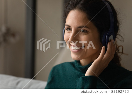 Young woman wearing earphones talking to customer online by videocall 85192753