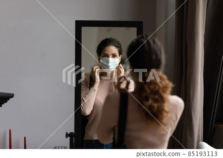 Mirror reflection of woman putting protective medical face mask Mirror reflection of woman putting protective medical face mask 85193113