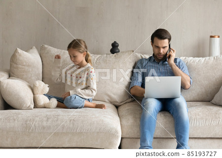 Concentrated young father working on laptop, while kid playing. 85193727