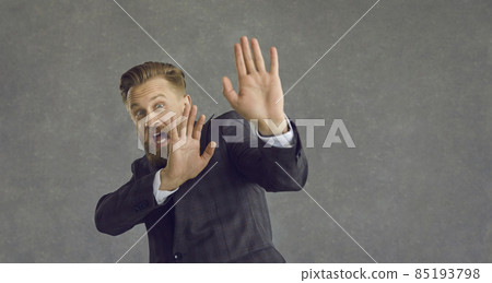 Caucasian middle-aged businessman with emotion of panic and fear on a gray background. Frightened man shouts and shows a stop sign. Concept of human emotions and facial expression. Caucasian middle-aged businessman with emotion of panic and fear on a gray background. Frightened man shouts and shows a stop sign. Concept of human emotions and facial expression. 85193798