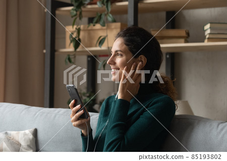 Millennial female listen to audio podcast in headset using smartphone 85193802