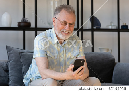 Happy mature 60s smartphone user reading text message on gadget 85194036