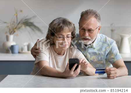 Serious older married couple shopping on internet stores 85194214