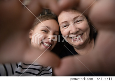 Old granny tween girl look at camera through finger heart 85194311