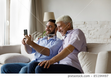 Happy two male generations family using cellphone. 85194497