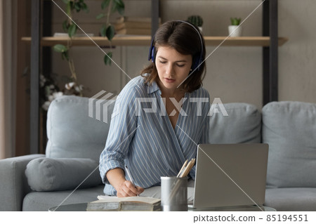 Serious young adult female student in headset listening audio seminar 85194551