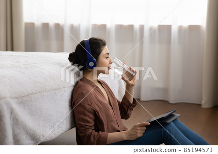 Relaxed young indian woman drinking glass of water. Relaxed young indian woman drinking glass of water. 85194571