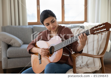 Happy young indian woman playing guitar at home. 85194643