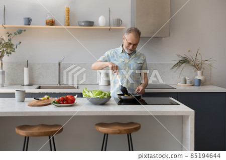 Mature 60s homeowner man cooking dinner in kitchen 85194644