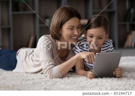 Smiling single mom show photo on tablet to preteen daughter Smiling single mom show photo on tablet to preteen daughter 85194717