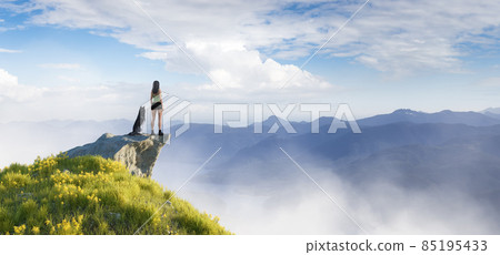 Adventurous Woman Hiking on top of a mountain with a Husky dog 85195433