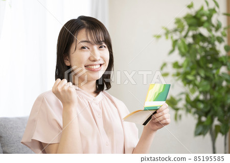 A woman looking at a bankbook and doing a guts pose A woman looking at a bankbook and doing a guts pose 85195585