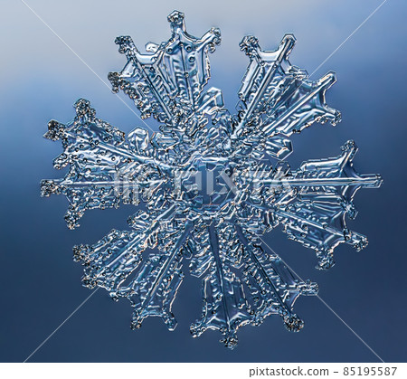 Snowflake on smooth gradient background. Macro photo of real snow crystal on glass surface. This is small snowflake with unusual pattern. Snowflake on smooth gradient background. Macro photo of real snow crystal on glass surface. This is small snowflake with unusual pattern. 85195587