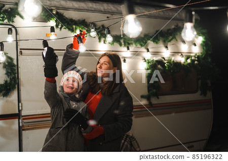 Caucasian woman and son decorate camper for christmas. Happy family travels in a mobile home. Caucasian woman and son decorate camper for christmas. Happy family travels in a mobile home. 85196322
