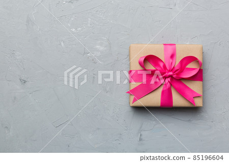 Holiday gift box wrapped in craft paper with colored bow on table background. Top view, flat lay, copy space 85196604