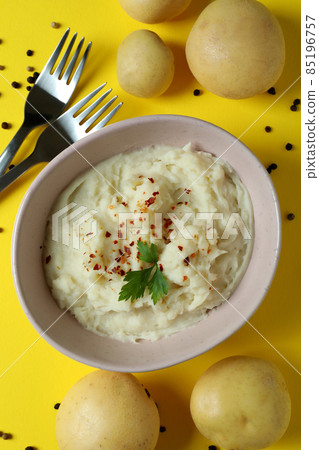 Plate of mashed potatoes and ingredients on yellow background 85196757