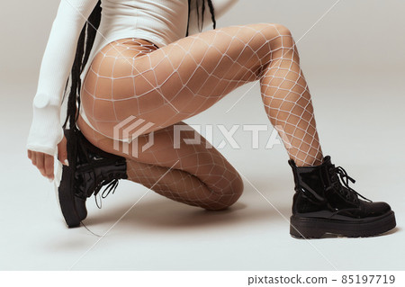 Close-up of woman feet with fishnet tights isolated on white background. Close-up of woman feet with fishnet tights isolated on white background. 85197719
