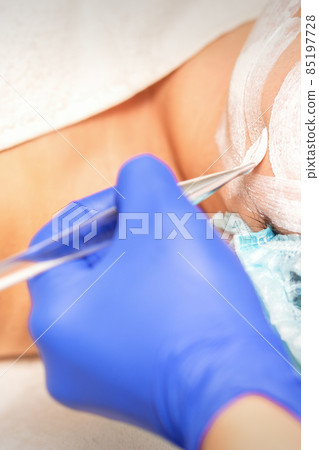 Face peeling at the beautician. Facial treatment. The beautician applies a cleansing face mask to the female patient. 85197728