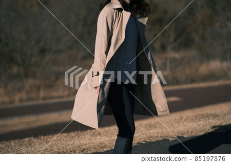 A woman in a trench coat fluttering in the wind 85197876