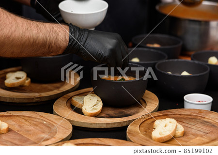 cooking process of Suquet de Peix soup with potatoes, herbs and fish with the addition of picada close-up in a saucepan on the table. 85199102