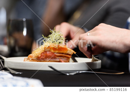 Man eating Francesinha, traditional Portuguese sandwich in a restaurant. National cuisine concept Man eating Francesinha, traditional Portuguese sandwich in a restaurant. National cuisine concept 85199116