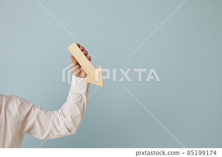 Man holding graph chart arrow that's pointing down on blue blank background with text copyspace. Business problems, profit decrease, lost money, income reduction, financial recession concept Man holding graph chart arrow that's pointing down on blue blank background with text copyspace. Business problems, profit decrease, lost money, income reduction, financial recession concept 85199174