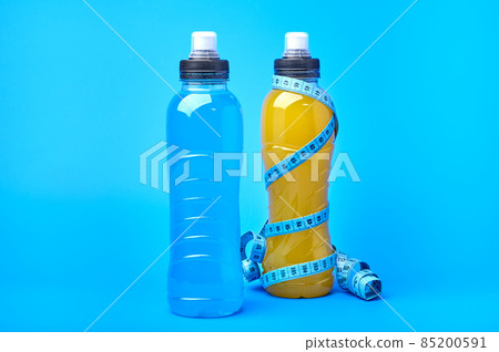 Isotonic energy orange yellow and blue sport drink in plastic bottles and measure tape Isotonic energy orange yellow and blue sport drink in plastic bottles and measure tape 85200591